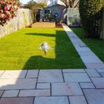 Raveena Indian Sandstone patio and path with a turfed lawn and softwood sleeper raised vegetable beds, constructed by LevelScape to combine aesthetic appeal with practical gardening.